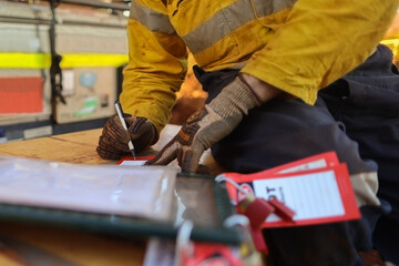 Safety practise construction worker setting and writing his name on personnel isolation red danger...