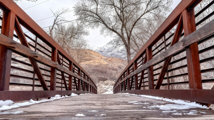 Panorama Melting snow on wooden landing of bridge with metal railing viewed in winter