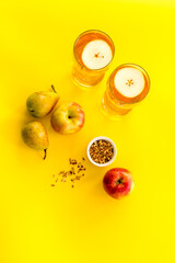 Fruit drinks with apple and pear on yellow table top-down