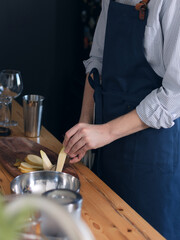 A man cook cooks in the kitchen in a blue apron, cuts a knife on the board with fruit