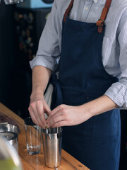 A man cook in a blue apron is cooking in the kitchen, the process of preparing a cocktail