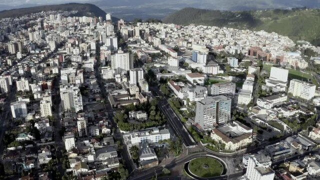 Drone shot of the city of Quito, Ecuador during quarantine. Overlooking buildings and houses of Avenue twelve of October. Empty streets with trees. Hills on the back and the valleys of the capital.