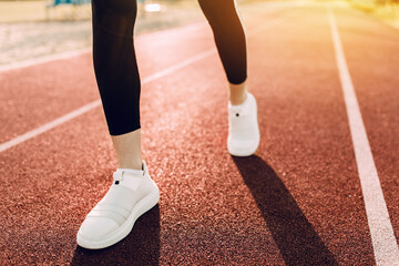 Fototapeta premium Close-up of women's feet in athletic shoes running around the stadium