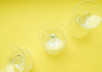 Three inverted crystal wine glasses on a yellow background