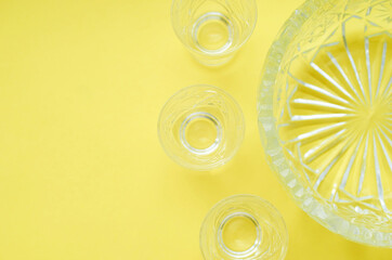 A crystal salad bowl and three glasses on a yellow background