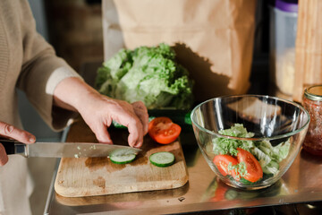 cropped view of senior woman cutting vegetables on board for salad on kitchen