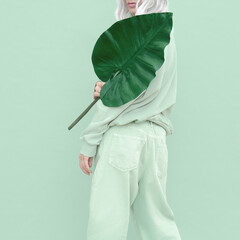 Hipster Girl posing in studio. Urban style. Fresh casual mint outfit. Fashion monochrome aesthetic colours.  Bio palm tropical mood