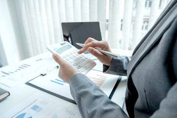 Business woman uses a calculator to calculate financial graphs that show results and analyze financial arrangements for business investment