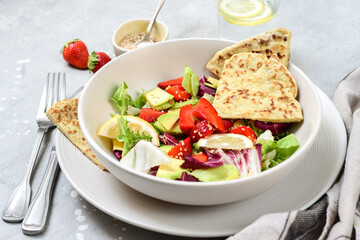 Green vegan salad from green leaves mix and vegetables. Top view on gray stone table