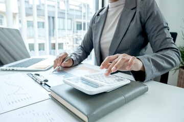 Business woman uses a calculator to calculate financial graphs that show results and analyze financial arrangements for business investment