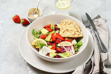 Green vegan salad from green leaves mix and vegetables. Top view on gray stone table
