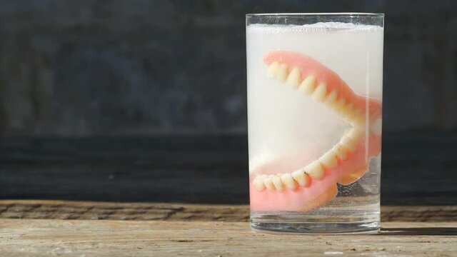 Teeth whitening concept. Medical denture smile jaws teeth on wooden background table, Teeth cleaning 1080p, Full HD, locked down.