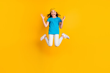 Fototapeta na wymiar Full size photo of crazy little lady jump high good mood celebrate competition winning unbelievable wear casual blue t-shirt headband trousers shoes isolated yellow color background