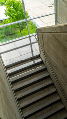 Vertical Commercial building interior with staircase and handrails between concrete walls