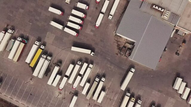 Aerial top down view of cargo trucks, containers at distribution warehouse.