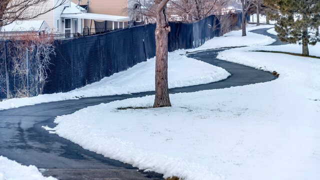 Panorama crop Curvy narrow road on snow covered ground in winter with houses background