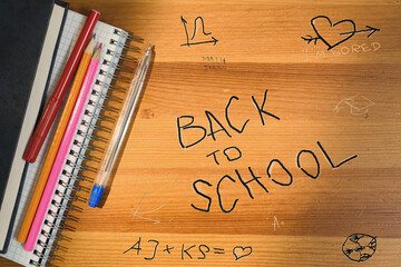 Back to school writing on wooden desk. Top view of school table with supplies and accessories. Shadow and sun beam overlay.
