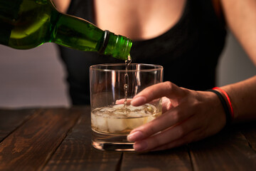 Drunk woman's hand putting on a glass of alcohol. Concept of alcoholism and addictions.