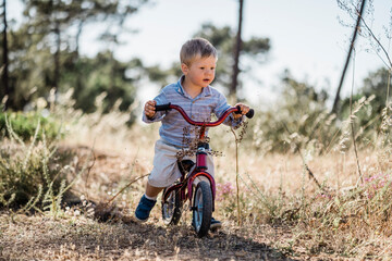 Cute toddler riding small bicycle in the forest