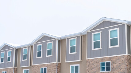Panorama frame Upper storey of townhomes with snowy pitched roofs on a cold winter day