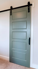 Vertical crop Closed sliding gray panel door with black handle against white wall of home