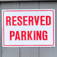 Square Reserved Parking sign board on a gray wooden wall topped with snow in winter