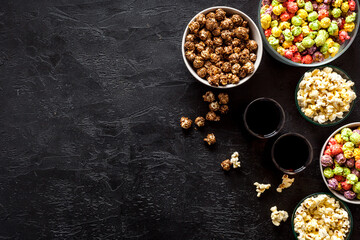 Set of flavored popcorn and soda on black table from above copy space