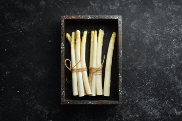 Raw white fresh asparagus on a black stone background. Healthy food. Top view. Free space for your...