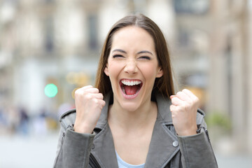 Excited woman celebrating good news in the street