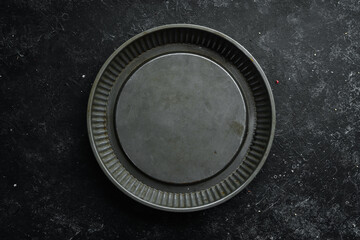 Metal kitchen form for baking food. On a black background. Top view. Free copy space.