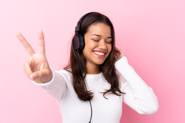 Fototapeta premium Young woman with earphones over isolated pink wall