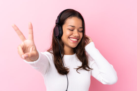 Young woman with earphones over isolated pink wall