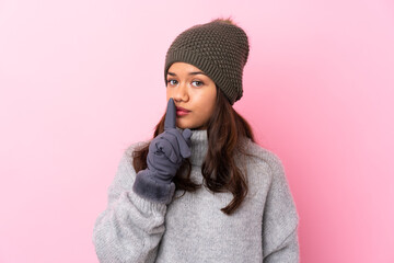 Young Colombian girl with winter hat over isolated pink wall doing silence gesture