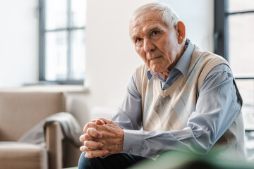 sad elderly man sitting alone on sofa during quarantine