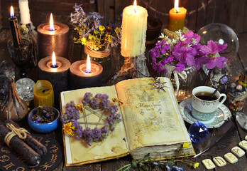 Open witch book with spells, black candles and cup of coffee. Esoteric, wicca and occult background...
