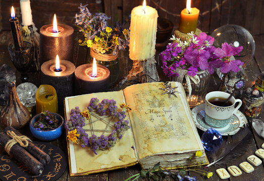 Open witch book with spells, black candles and cup of coffee. Esoteric, wicca and occult background with magic objects, fortune telling and divination ritual, Halloween mystic background.