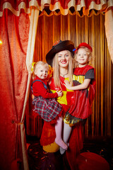 Family with dog during stylized theatrical circus photo shoot in beautiful red location. Model...