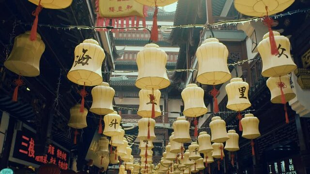 Panning slow motion view of lines of chinese yellow paper lanterns. Chinese idiomas symbol in the middle. Old ancient building in the background