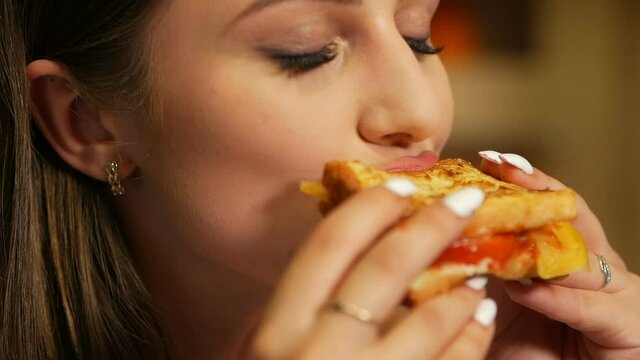 Girl passionately eats and bites a ketchup sandwich. Eat before bedtime.