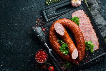 dried pork Salami sausage ring on a black stone background. Top view. Free space for text.