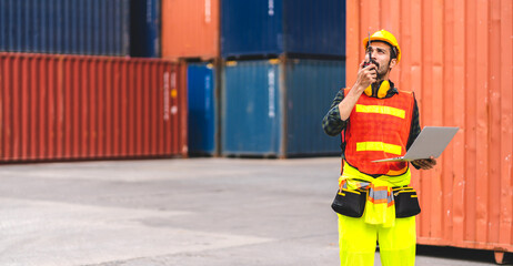 Professional engineer container cargo foreman in helmets working standing and using walkie talkie checking stock into container for loading.logistic and business export