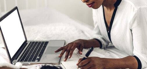 Young african american black woman relaxing and using laptop computer with white mockup blank screens.woman checking social apps and working.Communication and technology concept