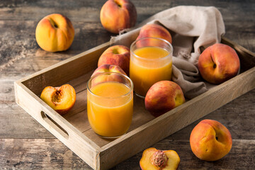 Natural peach juice in glass on wooden table	