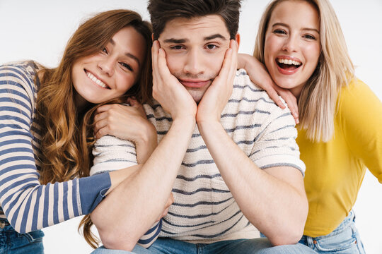 Image of unhappy man and cheerful women hugging and posing on camera