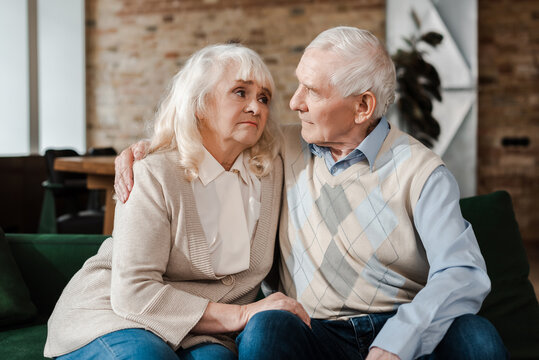 Sad Senior Couple Hugging On Sofa During Self Isolation