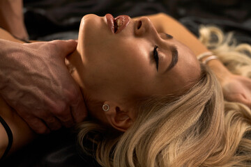 Close up portrait of a sexy young blonde with beautiful curly hair. Male hand touches.