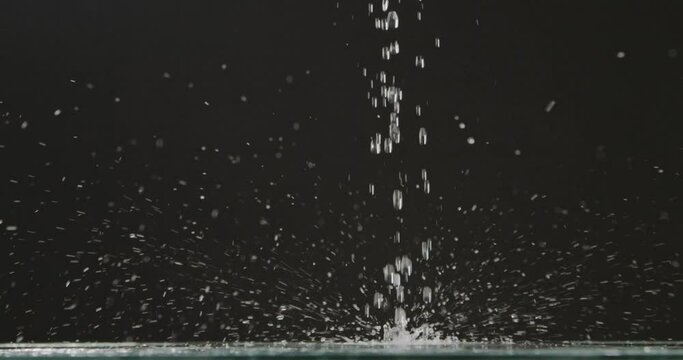 Running water and ripe blueberries fall from above with splashes and droplets of water, scattering in different directions against a black background. Slow motion. Full HD video, 240fps, 1080p