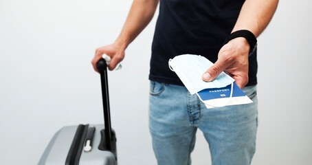 The man holds the passport with train ticket and the medical mask in hand  as an essential thing in travel in post covid-19 time