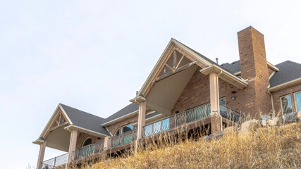 Panorama frame Hill top home exterior featuring stone brick wall and gable roofs over balcony