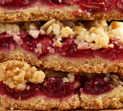 stack of square baked slices of cramble with red cherry,